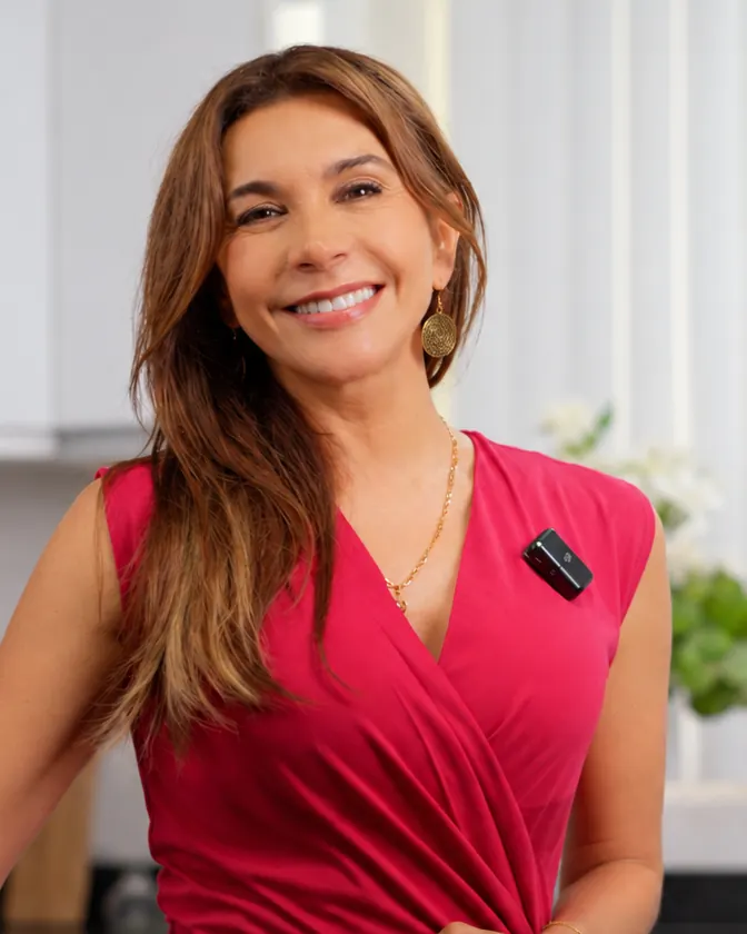 Julizza Pezo sonriendo en su cocina, con vestido rojo
